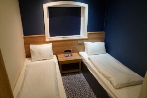 Cabin with two beds on board the ferry, blue walls, and closed curtains